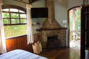 a living room with a stone fireplace and a television at Pousada Montserrat in Visconde De Maua