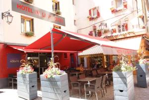 a restaurant with tables and chairs in front of a building at Hotel de la Placette Barcelonnette in Barcelonnette