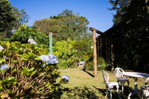 un jardín con mesa, sillas y flores en Pousada Montserrat, en Visconde De Maua