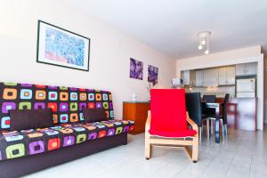 a living room with a red chair and a kitchen at Cabo Menor 2 Planet Costa Dorada in Salou