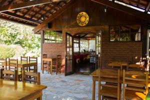 a restaurant with tables and chairs and a clock on the wall at Pousada Montserrat in Visconde De Maua