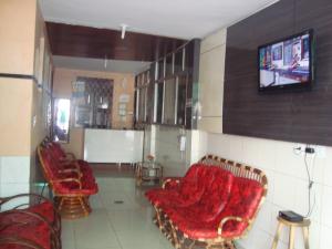 uma sala de estar com cadeiras e uma televisão na parede em Pousada Vianna's em Fortaleza