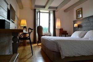 a bedroom with a bed and a desk and a window at La Maison Des Jardins in Auriac