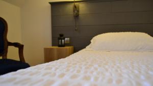 a bedroom with a white bed and a chair at La Maison Des Jardins in Auriac +2 photos
