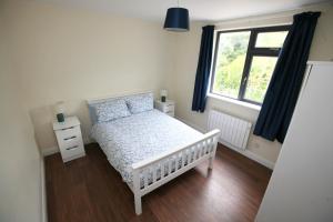 - une chambre avec un lit bébé blanc et une fenêtre dans l'établissement Harbour front apartments, à Burtonport