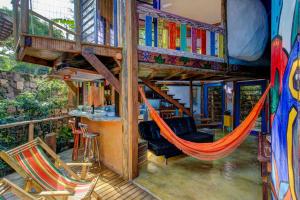 a hammock in the middle of a house with books at Sea View Colorful House in Ilhabela