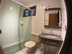 a bathroom with a shower and a sink and a toilet at Pousada La Luna - Frente Mar in Barra Velha