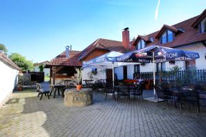 patio ze stołami, krzesłami i parasolami na domu w obiekcie Restaurant penzion u Buchlovskeho zamku w mieście Buchlovice