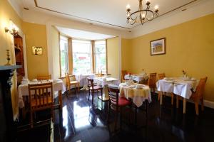 un ristorante con tavoli e sedie bianchi e un lampadario a braccio di Talisker Guest House a Inverness