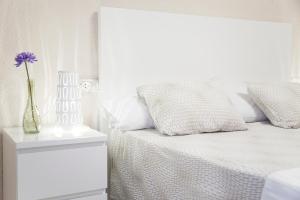 a white bedroom with a bed with a vase with a flower in it at Apartamento Cardenal in Valencia