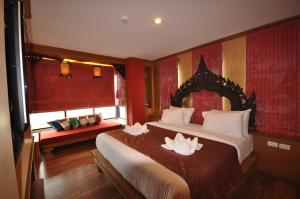 Un dormitorio con una cama grande con dos lirios. en Chalelarn Hotel Hua Hin, en Hua Hin