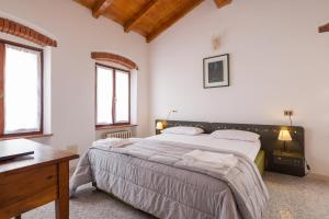 a bedroom with a large bed and two windows at Locanda Al Centrale in Caprino Veronese