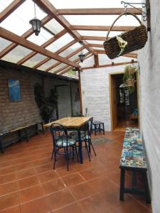 un patio con pérgola de madera, mesa y sillas en Hospedaje Higueron, en Baños