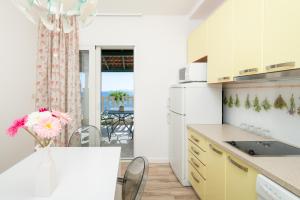 una cocina con armarios amarillos y una mesa con un jarrón de flores en Superb Beachfront Luxury Seaview with Private Beach, en Hvar