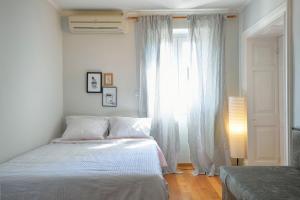 a white bedroom with a bed and a window at "San Giacomo Square Apt." in the heart of old town in Corfu