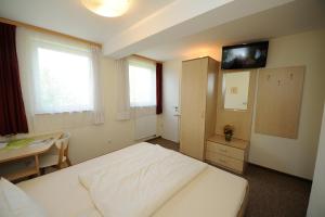 Schlafzimmer mit einem Bett, einem Schreibtisch und einem TV in der Unterkunft Gästehaus Südheide in Hambühren