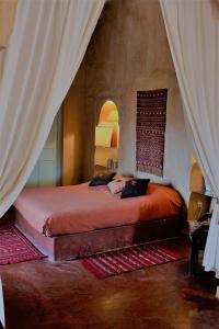 a bedroom with a bed in a room with curtains at Hotel De Charme Les 3 Chameaux 4 étoiles in Mirleft