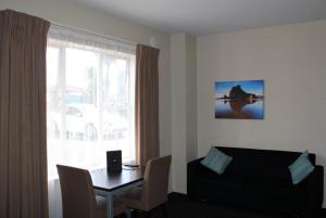 a living room with a table and a couch and a window at 540 on Great South Motel in Auckland