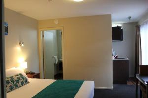a hotel room with a bed and a bathroom at 540 on Great South Motel in Auckland