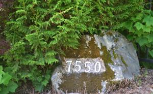 um sinal numa rocha em frente a uma árvore em The Rockwell-Harrison Guest Lodge em Harrison Hot Springs