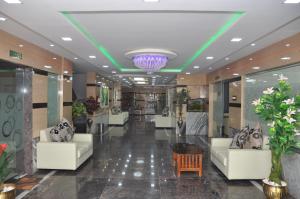 un vestíbulo con 2 sofás blancos y una lámpara de araña en Hotel Green Palace, en Thanjāvūr
