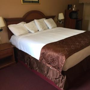 a hotel room with a large bed with white sheets at Shamrock Motel Hot Springs in Hot Springs
