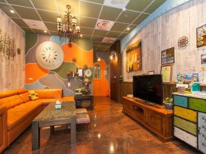 a living room with an orange couch and a tv at Kimoge Homestay in Hualien City