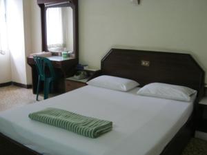 - une chambre avec un lit et une serviette verte dans l'établissement Ho Fah Hotel, à Phatthalung