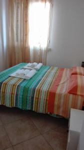 CasamassellaにあるCasa Vacanze Paianoのカラフルな毛布と窓が備わるベッド