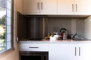 a kitchen with white cabinets and a sink at Eagle Peaks at Freycinet in Coles Bay
