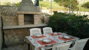 una mesa con 4 sillas blancas y un horno de piedra en Family apartments Grguric en Pag