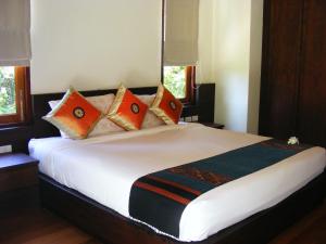 a bedroom with a large bed with orange and black pillows at Baan Nana Villa in Mae Nam