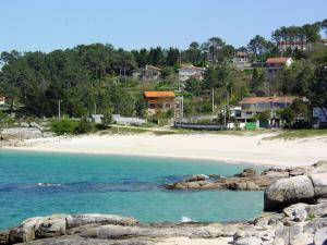 a beach with rocks in the water and houses at Apartamento A Canteira in O Grove