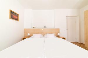 a white bedroom with a large white bed at Forestine Guesthouse in Hévíz