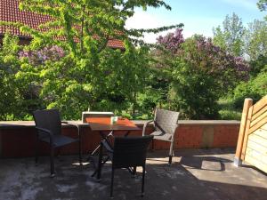 une terrasse avec trois chaises, une table et un arbre dans l'établissement Pension Gutshaus, à Halle-sur-Saale