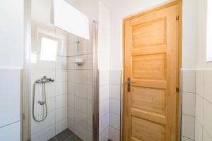 ein Badezimmer mit einer Dusche und einer Holztür in der Unterkunft Forestine Guesthouse in Hévíz