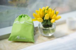a green bag sitting next to a vase of yellow flowers at iclub To Kwa Wan Hotel in Hong Kong +19 photos