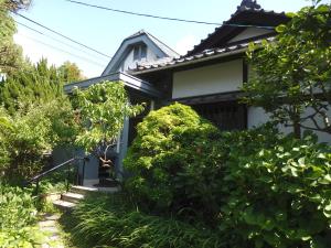 una casa bianca con cespugli verdi di fronte di Guesthouse Tamura a Nara