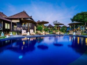 a pool at a resort with chairs and umbrellas at Bali Belva in Nusa Lembongan