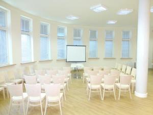 Duży pokój z białymi krzesłami i ekranem w obiekcie Hotel Giżycko w mieście Giżycko