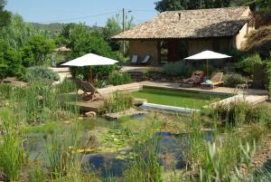 una piscina en un jardín con sillas y una casa en Quinta do Arade - casa 4 pétalas, en Barranco do Resgalho