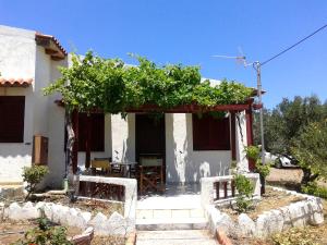 ein weißes Haus mit einer Pergola mit einem Tisch und Stühlen in der Unterkunft Sunrise Apartments in Palekastro