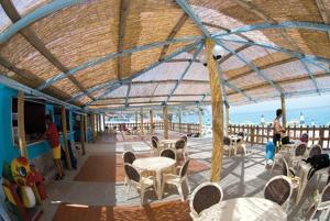 una terraza cubierta con mesas y sillas y el océano en Villaggio Hotel Club La Pace en Tropea