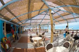 a covered deck with tables and chairs and the ocean at Villaggio Hotel Club La Pace in Tropea