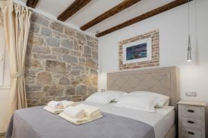 a bedroom with two beds and a stone wall at Split Inn Apartments in Split