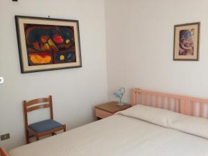 カーラゴノネにあるAppartamento IGNIS Cala Gononeのベッドルーム1室(ベッド1台、椅子、絵画付)
