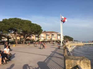 eine Gruppe von Menschen, die auf einem Bürgersteig neben dem Wasser sitzen in der Unterkunft Villa Pagnol in Andernos-les-Bains