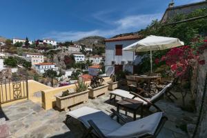 a patio with tables and chairs and an umbrella at Villa Sunrise in Hydra