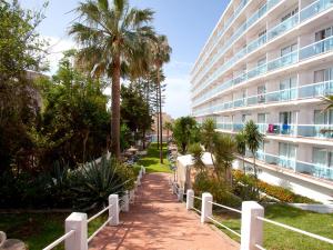 a walkway in front of a building with palm trees at Hotel Palia Las Palomas in Torremolinos