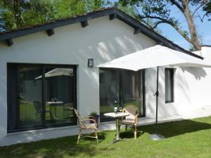 Casa blanca con mesa, sillas y sombrilla en A l'Heure d'Eté, en Fargues-de-Langon